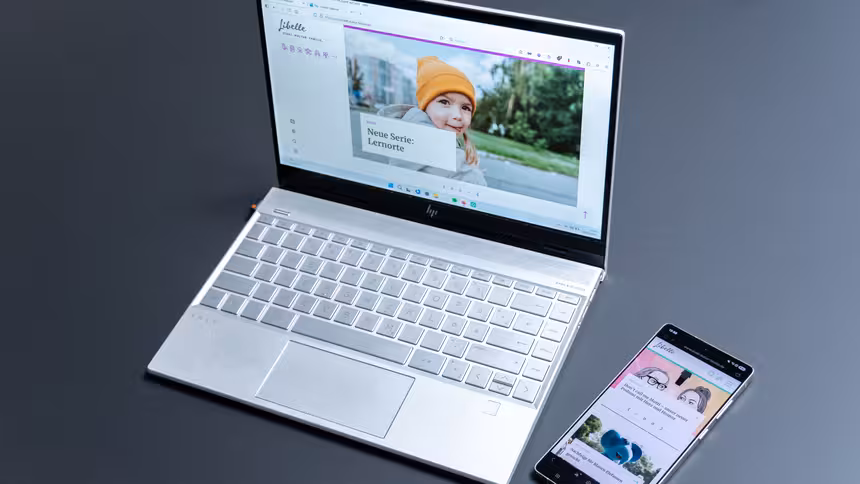 Ein Laptop und ein Smartphone, auf denen die Website des Libelle Magazins angezeigt wird, liegen auf einem Tisch