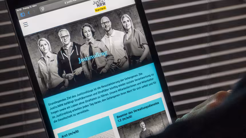 Eine Person hält ein Tablet, auf dem die Karriereseite der Justiz NRW aufgerufen ist.
